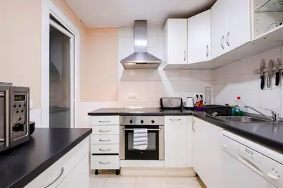 a kitchen with white cabinets and black counter tops at Three Bedroom Apartment in Sants in Barcelona