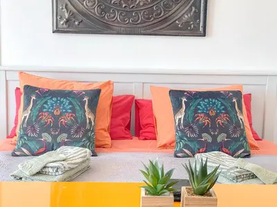 a bed with colorful pillows and plants on it at Unique studio Apartment with amazing terrace Sitges centre beach in Sitges