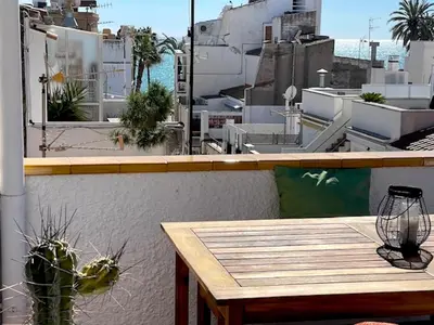 a table on a balcony with a view of a city at Unique studio Apartment with amazing terrace Sitges centre beach in Sitges