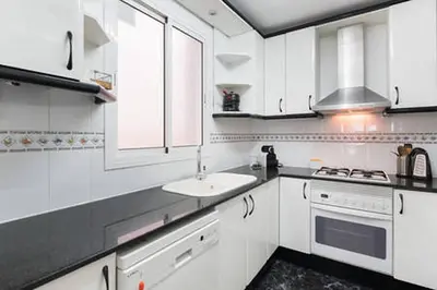 a white kitchen with a sink and a stove at 3 bedroom Apartment with private garden on top location Sitges centre beach in Sitges