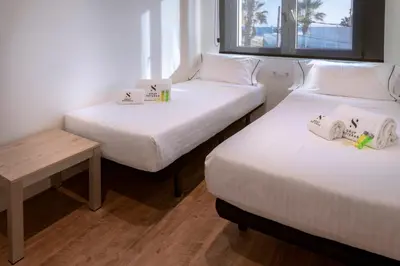 two beds in a small room with a table and a bed at Apartments Playa de Castelldefels in Castelldefels