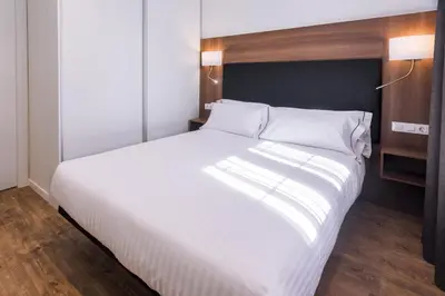a bedroom with a large white bed with white pillows at Apartments Playa de Castelldefels in Castelldefels