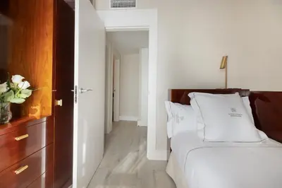 a bedroom with a bed with white sheets and a drawer at Suites Center Barcelona in Barcelona