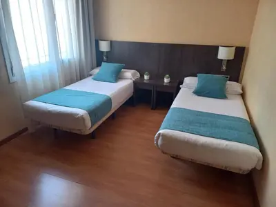 two beds in a hotel room with blue pillows at Hotel 1948 Manresa in Manresa