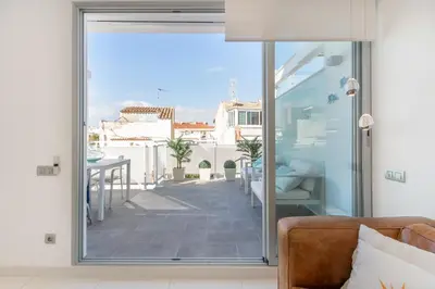 a living room with a sliding glass door to a balcony at Beach penthouse Sitges Rentals in Sitges
