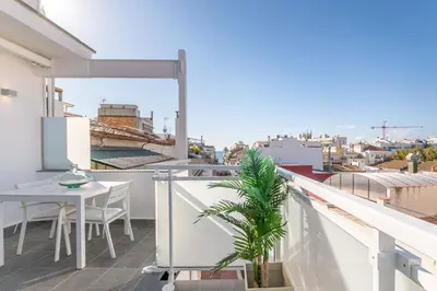 a balcony with a table and a palm tree on it at Beach penthouse Sitges Rentals in Sitges