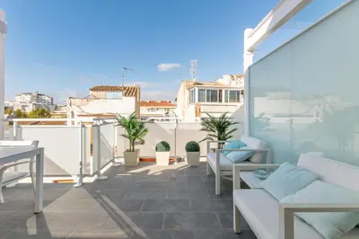 a balcony with white furniture and potted plants at Beach penthouse Sitges Rentals in Sitges