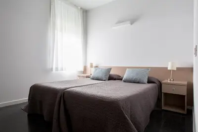 a bedroom with a bed with a blanket and a window at Residencia Universitaria Resa Roberto de Nobili in Sant Cugat del Vallès