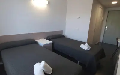 two beds in a hotel room with towels on them at Residencia Universitaria Resa Roberto de Nobili in Sant Cugat del Vallès