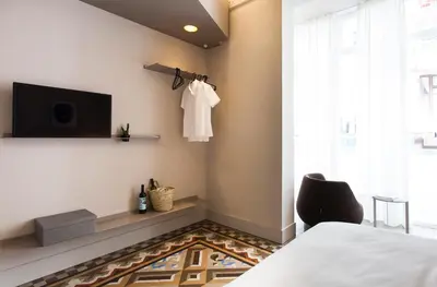 a bedroom with a bed and a chair and a television at DestinationBCN - Universitat Rooms in Barcelona