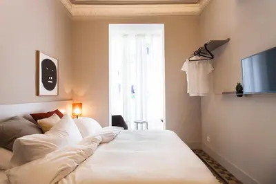 a white bed in a room with a window at DestinationBCN - Universitat Rooms in Barcelona
