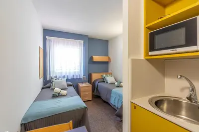 a small room with two beds and a sink at Residencia Universitaria Resa La Ciutadella in Barcelona