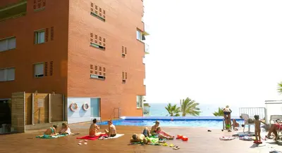 a group of people sitting around a swimming pool at Great Sea-Side Barcelona Apartment in Badalona