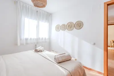 a white bedroom with a bed with towels on it at Capricho Apartamento Sitges in Sitges