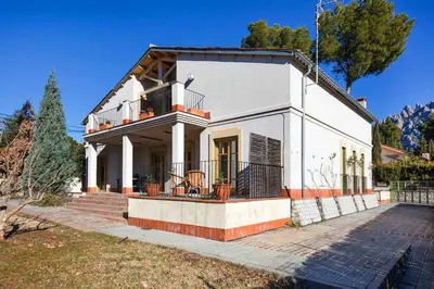 a white house with a porch and a balcony at Xalet de la Muntanya, El Bruc-Montserrat in El Bruc