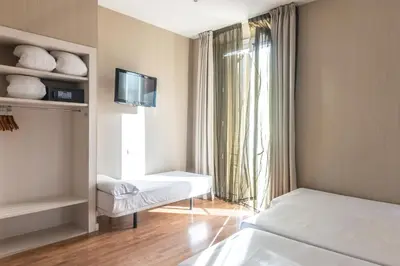 a room with two beds and a tv and a window at Hostal BCN Ramblas in Barcelona