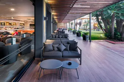 a lobby with couches and tables and palm trees at Hotel President in Calella