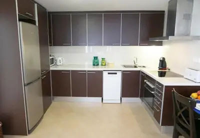 a kitchen with brown cabinets and a white refrigerator at Love Sitges & Beach in Sitges