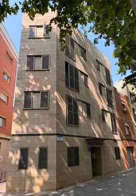 a tall brick building with windows on a street at Hostal Rambla in Sant Boi del Llobregat