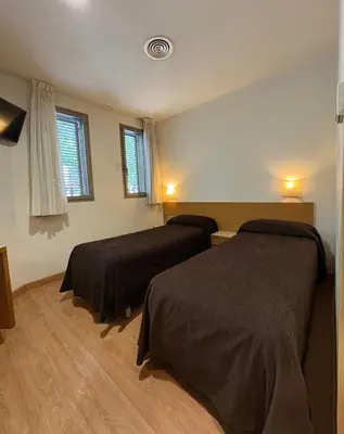 a bedroom with two beds and two windows at Hostal Rambla in Sant Boi del Llobregat