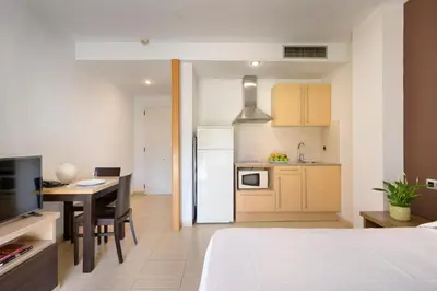 a room with a bed and a kitchen with a table at SG Marina 54 Apartments in Castelldefels