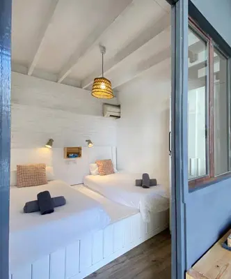 two beds in a white room with a window at Fridays Flats Casa Lavander in Barcelona