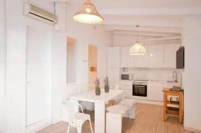 a white kitchen with a white table and chairs at Fridays Flats Villa Alba in Barcelona