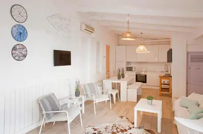 a living room with white furniture and a clock on the wall at Fridays Flats Villa Alba in Barcelona