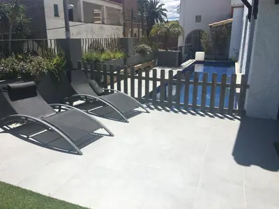 two chairs sitting on a patio next to a fence at Villa Masnou Homelydays in El Carrer del Canonge