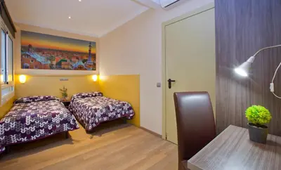 a hotel room with two beds and a table at Hostal Barcelona in Barcelona