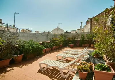 a row of white benches on a patio with plants at Diagonal Apartments in Barcelona