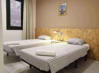 three beds in a hotel room with striped sheets at Diagonal Apartments in Barcelona