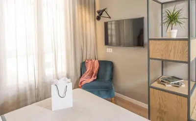a living room with a blue chair and a television at Mosaic by Ona in Barcelona