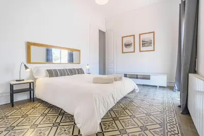 a white bedroom with a large bed and a lamp at Casa Premia in Premiá de Mar