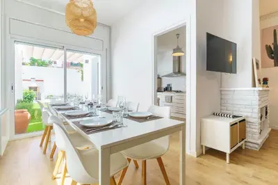 a white dining room with a long table and white chairs at Casa Premia in Premiá de Mar