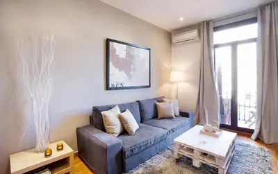 a living room with a blue couch and a table at Apartments Barcelona & Home Deco Viladomat in Barcelona