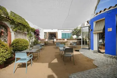 a patio with tables and chairs next to a blue building at B&B Sant Pol - Adults Only in San Pol de Mar