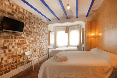 a bedroom with two beds and a brick wall at B&B Sant Pol - Adults Only in San Pol de Mar