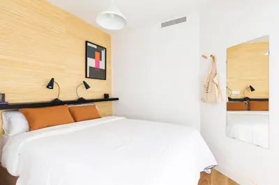 a bedroom with a white bed with orange pillows at WOW Apartments by Olala Homes in Hospitalet de Llobregat