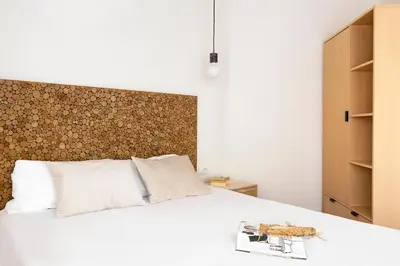 a bedroom with a white bed with a wooden headboard at WOW Apartments by Olala Homes in Hospitalet de Llobregat