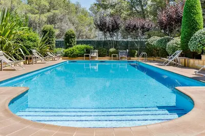 a swimming pool with blue water in a yard at Hotel Desitges in Sant Pere de Ribes