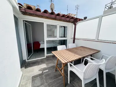 a small balcony with a wooden table and white chairs at Rainbow Apartments BY BLAUSITGES in Sitges