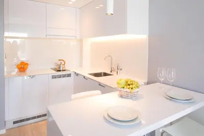 a white kitchen with a table with a bowl of fruit at Masd Mediterraneo Hotel Apartamentos Spa in Castelldefels