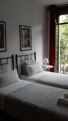 two beds sitting in a bedroom with a window at Hostal Absolut Stay in Barcelona
