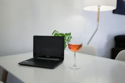 a glass of wine next to a laptop on a table at Tendency Apartments Fira in Hospitalet de Llobregat