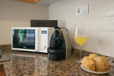 a coffee maker next to a microwave and a glass of wine at Tendency Apartments Fira in Hospitalet de Llobregat