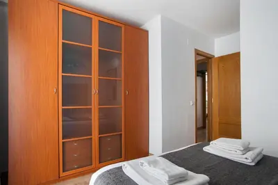 a bedroom with a wooden cabinet with towels on a bed at Tendency Apartments Fira in Hospitalet de Llobregat