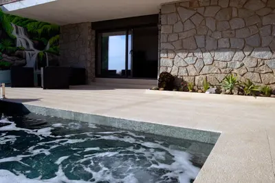 a house with a swimming pool next to a stone wall at Apartment Pearl of Cabrils in Cabrils