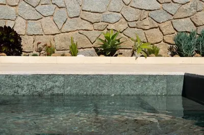 a swimming pool in front of a stone wall at Apartment Pearl of Cabrils in Cabrils