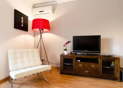 a living room with a white chair and a television at Valencia Suite ArchsenseApartments in Barcelona